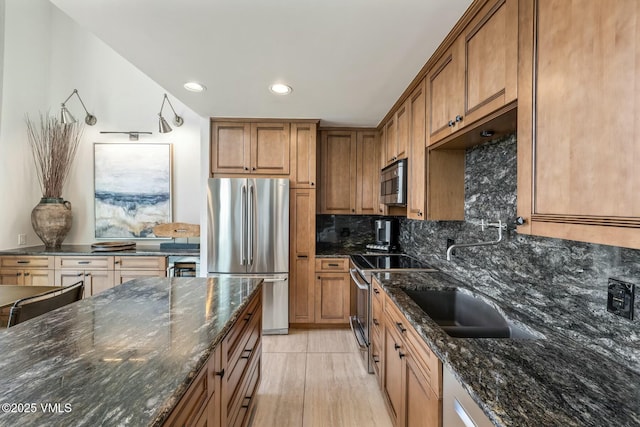 kitchen with brown cabinets, recessed lighting, decorative backsplash, appliances with stainless steel finishes, and dark stone countertops