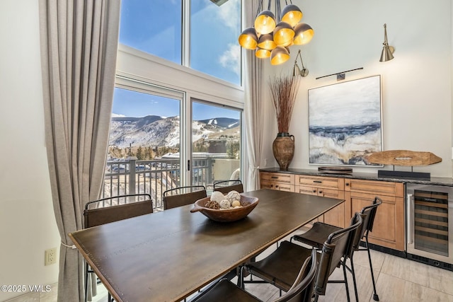 dining room with light tile patterned flooring, a mountain view, a notable chandelier, beverage cooler, and a high ceiling