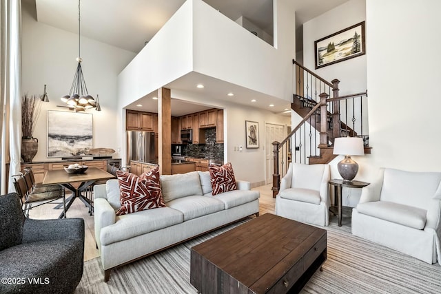 living room with stairs, a high ceiling, recessed lighting, and a notable chandelier