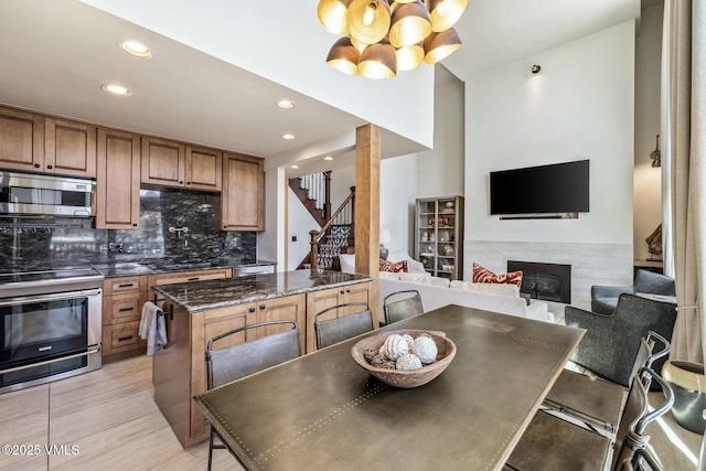 dining room with recessed lighting, stairs, a notable chandelier, and a tile fireplace