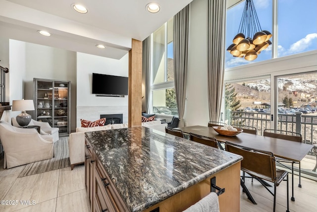 kitchen featuring dark stone counters, a glass covered fireplace, open floor plan, a notable chandelier, and recessed lighting