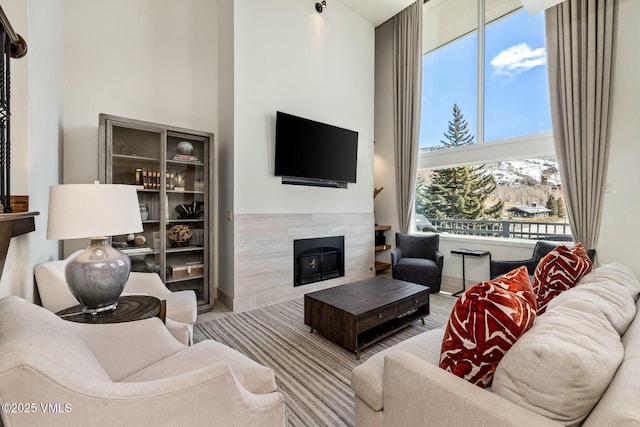 living room with a high ceiling and a tiled fireplace