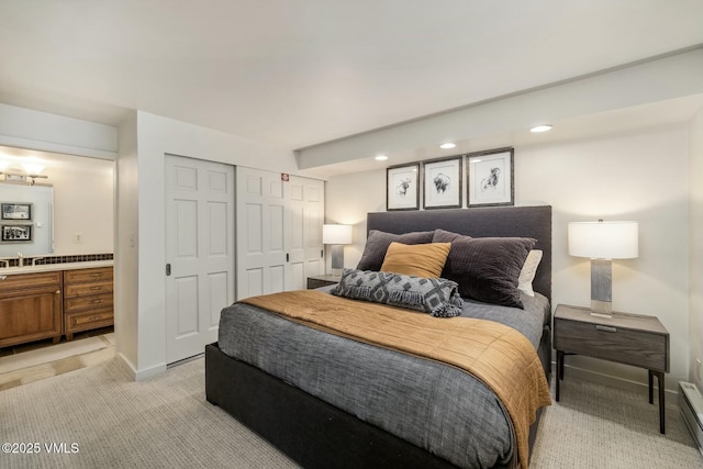 bedroom with a baseboard radiator, a closet, light colored carpet, ensuite bath, and baseboards