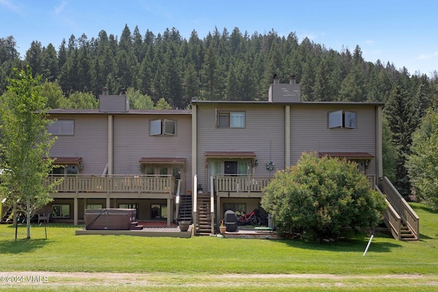 rear view of house featuring a hot tub, a yard, and a deck