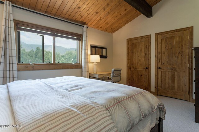 bedroom with a mountain view, wood ceiling, vaulted ceiling with beams, and carpet flooring