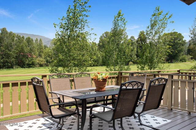 wooden terrace featuring a mountain view and a lawn