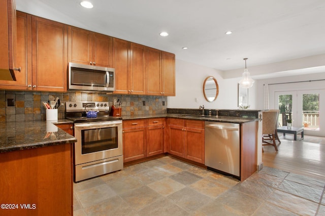 kitchen featuring sink, decorative light fixtures, kitchen peninsula, stainless steel appliances, and decorative backsplash