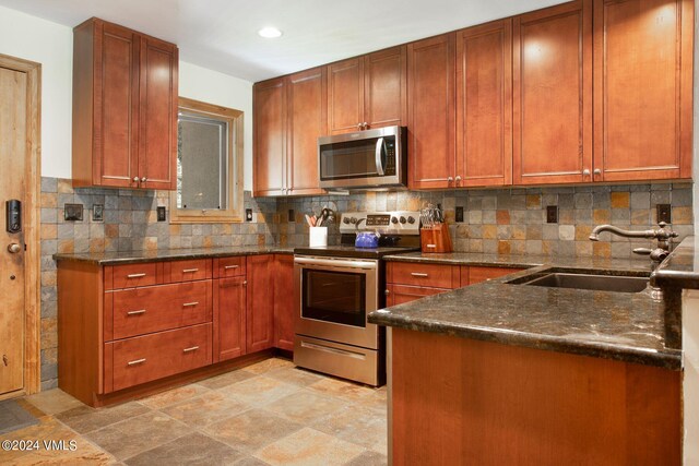 kitchen featuring sink, backsplash, stainless steel appliances, and dark stone counters