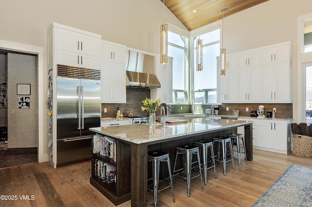 2682 E Haystacker Dr, Eagle, CO 81631 - kitchen featuring stainless steel built in fridge, wall chimney exhaust hood, light wood-style flooring, a large island, and high vaulted ceiling