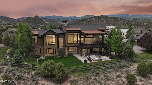 2682 E Haystacker Dr, Eagle, CO 81631 - back of property at dusk with a fire pit, stone siding, a patio, a chimney, and a fenced backyard