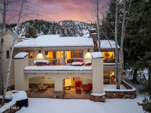 snow covered house featuring a balcony and a mountain view