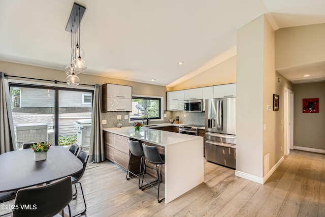 11 Spruce Cir, Edwards, CO 81632 - kitchen featuring appliances with stainless steel finishes, a peninsula, light countertops, tasteful backsplash, and a breakfast bar