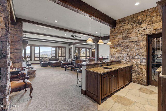 kitchen with pendant lighting, sink, dark stone countertops, a breakfast bar area, and dark brown cabinets