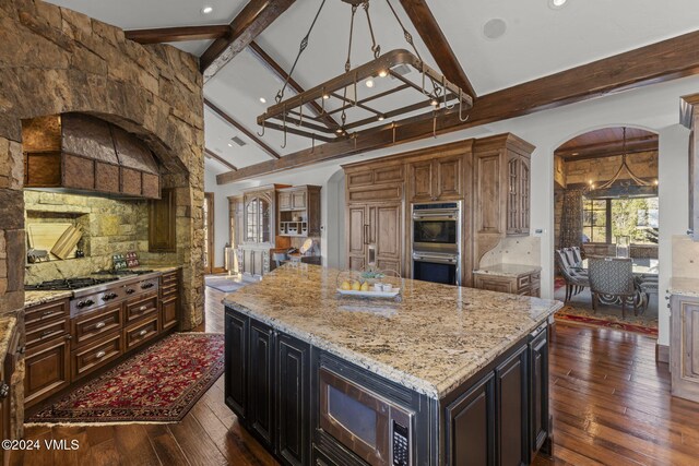 kitchen featuring beamed ceiling, a center island, built in appliances, and dark hardwood / wood-style flooring