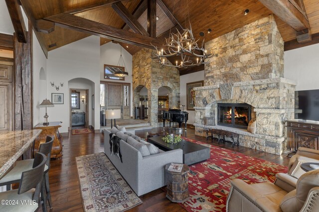 living room featuring a stone fireplace, dark hardwood / wood-style floors, wooden ceiling, and beam ceiling