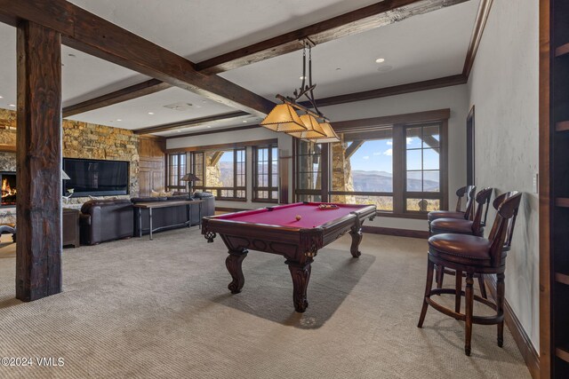 rec room featuring billiards, beam ceiling, a mountain view, a stone fireplace, and light colored carpet