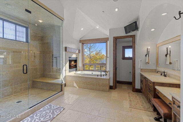 bathroom featuring vanity, a wealth of natural light, shower with separate bathtub, and vaulted ceiling