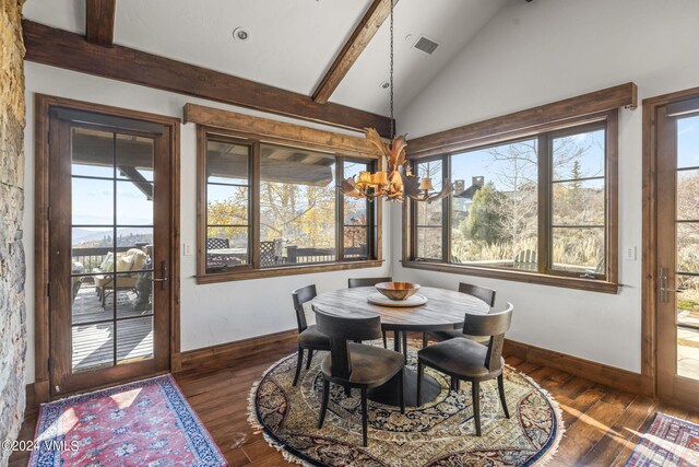 dining room with lofted ceiling with beams, dark wood-type flooring, and a chandelier