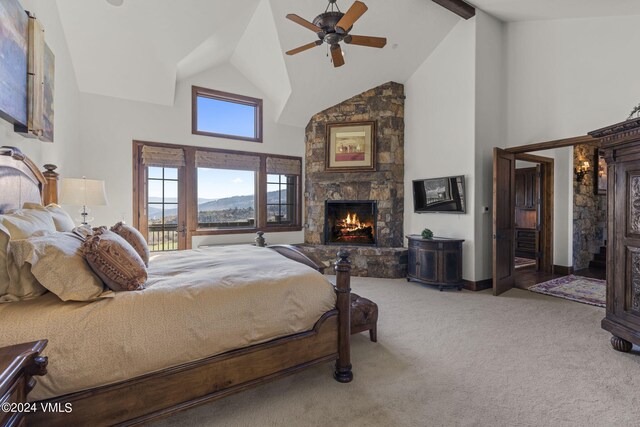 bedroom featuring a stone fireplace, high vaulted ceiling, beamed ceiling, carpet, and a mountain view