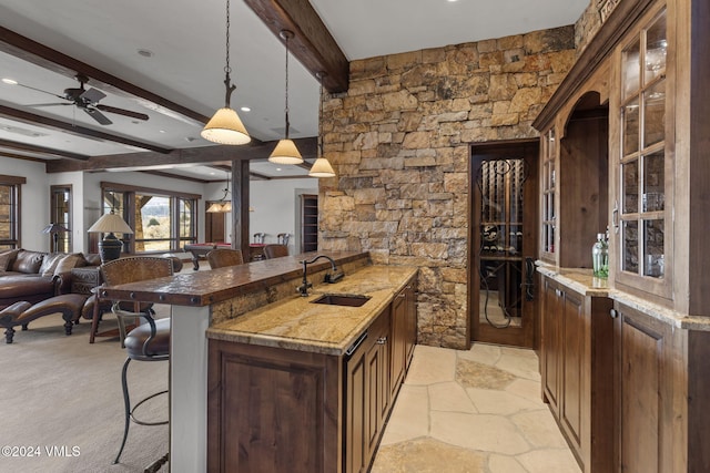 kitchen with sink, a breakfast bar area, hanging light fixtures, dark stone countertops, and beam ceiling