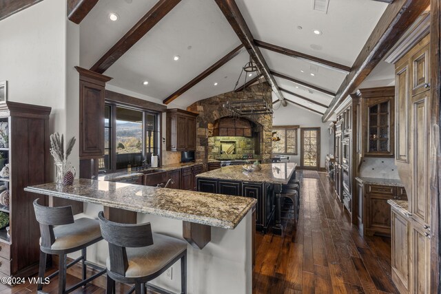 kitchen featuring light stone counters, dark hardwood / wood-style floors, beamed ceiling, a large island, and backsplash