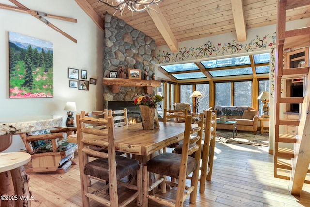 dining space with high vaulted ceiling, a fireplace, light hardwood / wood-style floors, wooden ceiling, and beam ceiling