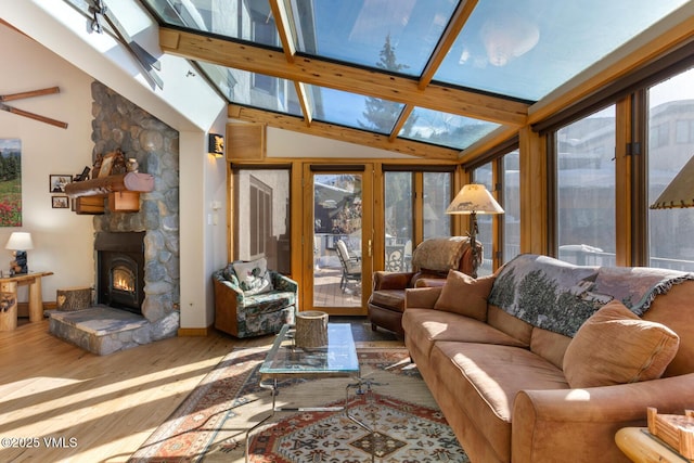 living room with wood-type flooring, a stone fireplace, and high vaulted ceiling