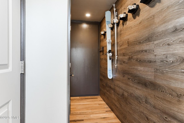 hallway with hardwood / wood-style flooring and wooden walls