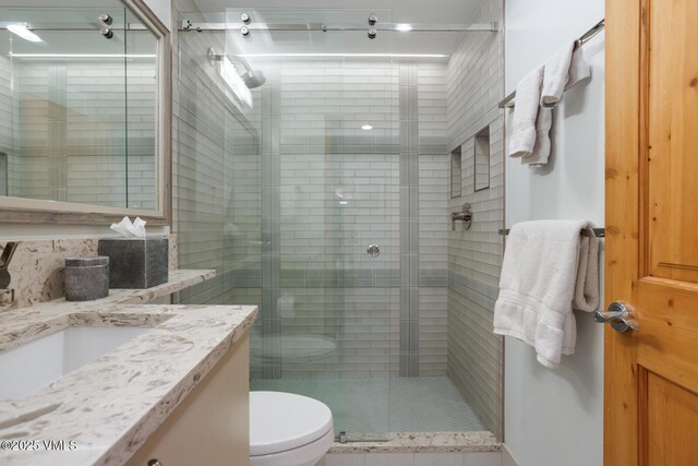 bathroom with walk in shower, vanity, and toilet