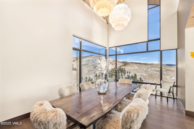 dining space featuring a mountain view, a healthy amount of sunlight, an inviting chandelier, and dark hardwood / wood-style flooring