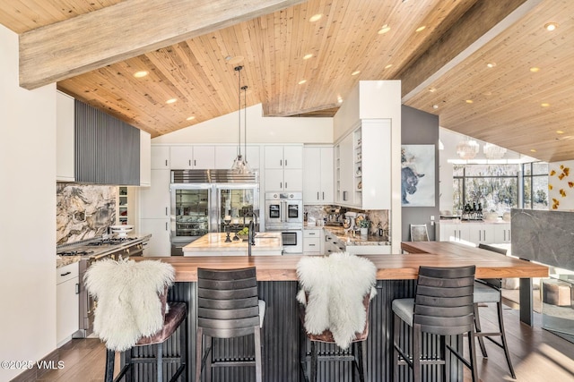 kitchen featuring high end appliances, white cabinetry, and wood counters