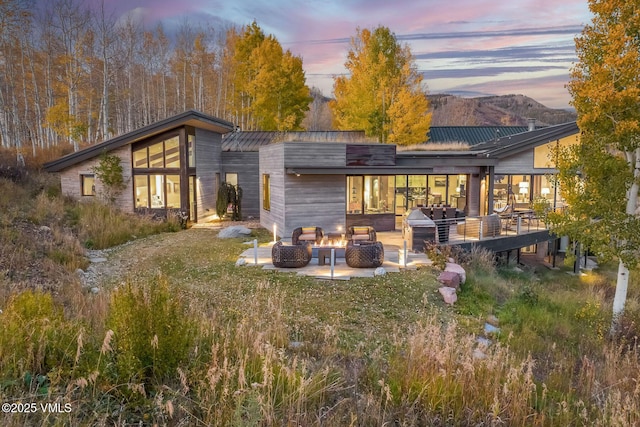 back house at dusk with a fire pit and a patio area