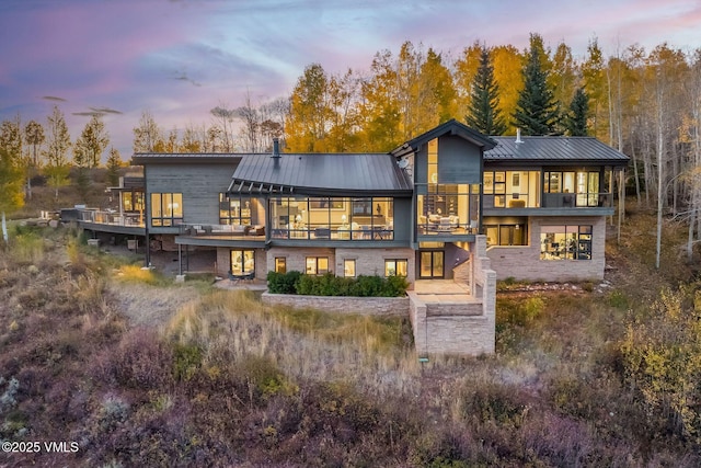 back house at dusk featuring a balcony