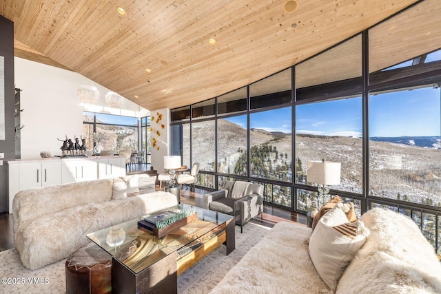 living room with vaulted ceiling, light hardwood / wood-style flooring, wooden ceiling, a mountain view, and expansive windows