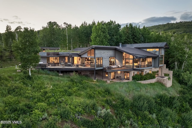 1268 Paintbrush, Avon, CO 81620 - back of property featuring a wooded view, a metal roof, stone siding, and a wooden deck