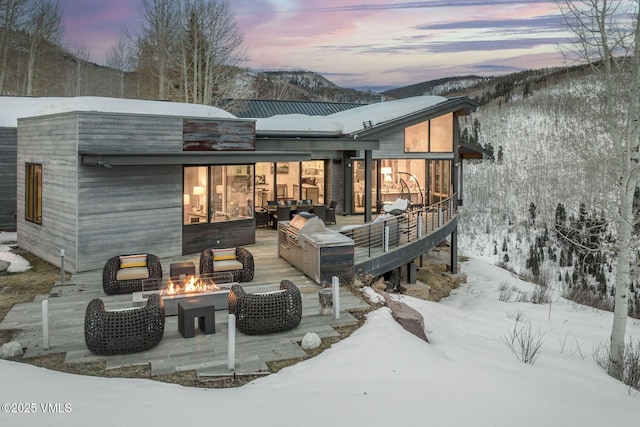 snow covered house featuring a mountain view and an outdoor living space with a fire pit