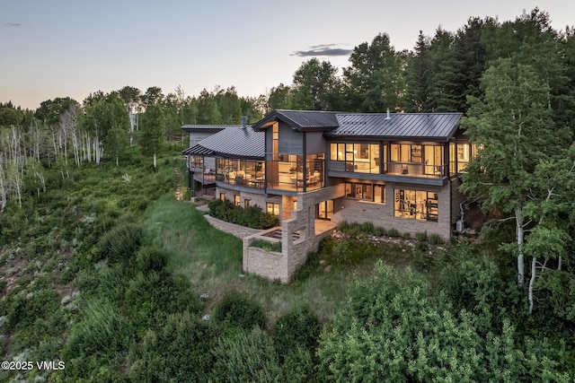 1268 Paintbrush, Avon, CO 81620 - back of house at dusk featuring a standing seam roof, a metal roof, and a balcony