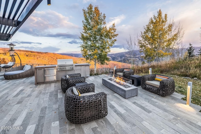 patio terrace at dusk with a grill, a mountain view, area for grilling, and an outdoor fire pit