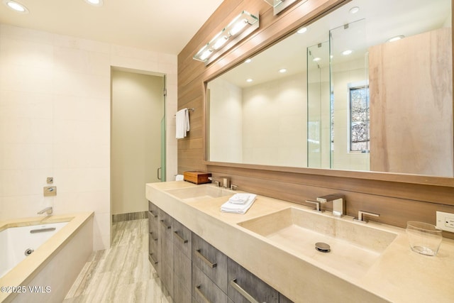 bathroom with vanity, shower with separate bathtub, and tile walls