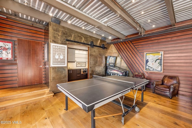 rec room with a barn door and light wood-type flooring