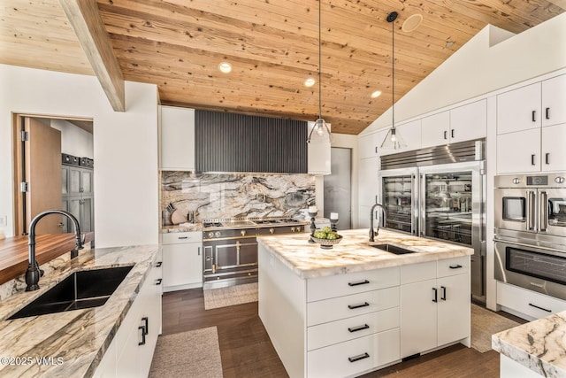 kitchen featuring a kitchen island with sink, sink, and white cabinets