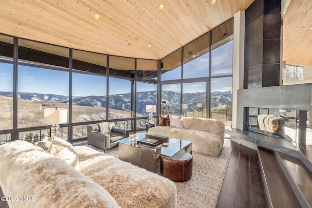 living room featuring hardwood / wood-style flooring, wooden ceiling, a mountain view, a tile fireplace, and expansive windows