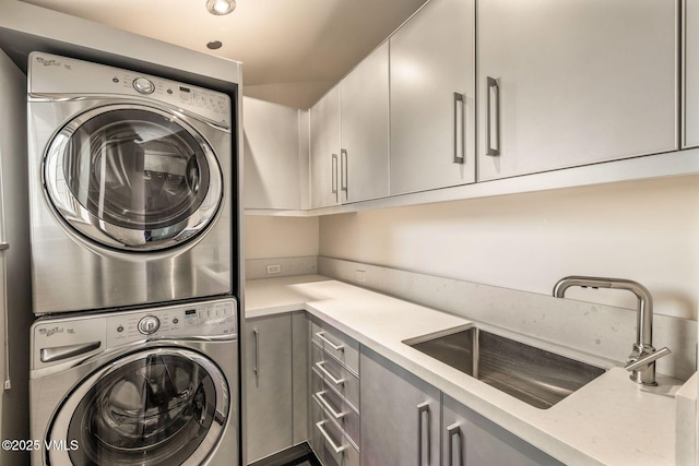 laundry area with sink, cabinets, and stacked washer / dryer