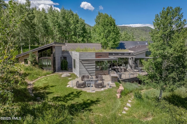 1268 Paintbrush, Avon, CO 81620 - rear view of property with a deck with mountain view, a fire pit, a lawn, a metal roof, and a patio