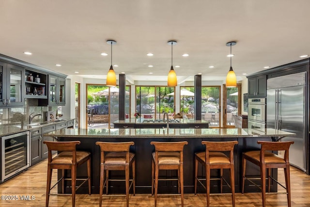 225 Eagle Crest Rd, Edwards, CO 81632 - indoor wet bar with appliances with stainless steel finishes, wine cooler, light wood-type flooring, recessed lighting, and hanging light fixtures