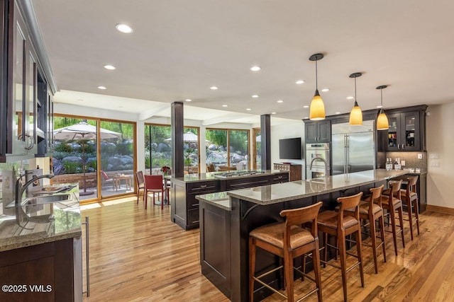 225 Eagle Crest Rd, Edwards, CO 81632 - kitchen with stainless steel appliances, a large island with sink, light wood finished floors, recessed lighting, and a breakfast bar