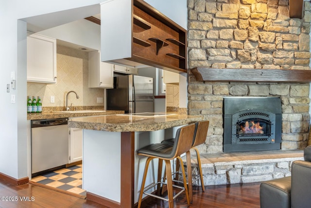 89 Columbine Cir Unit 2, Avon, CO 81620 - kitchen with appliances with stainless steel finishes, white cabinets, tile counters, a kitchen bar, and a fireplace