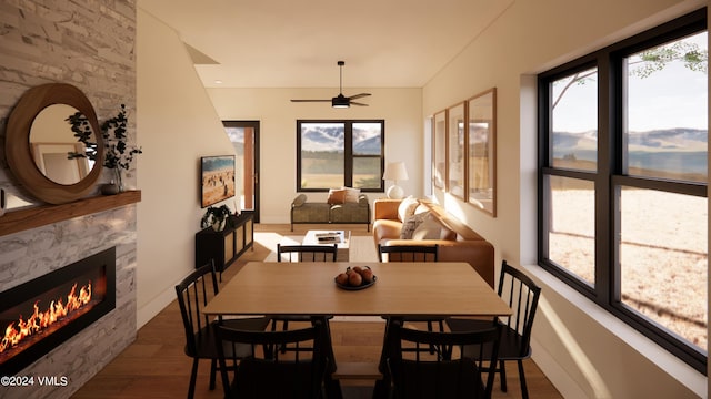 dining space featuring dark wood-type flooring, ceiling fan, a premium fireplace, and a wealth of natural light