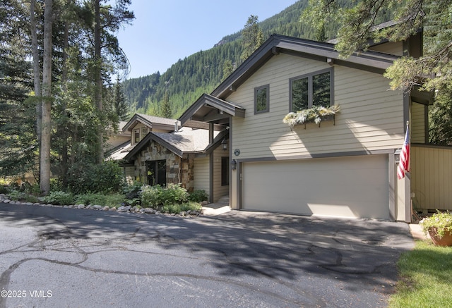 4030 Bighorn Rd Lot 1-B, Vail, CO 81657 - view of front of house with a mountain view, a garage, asphalt driveway, and stone siding