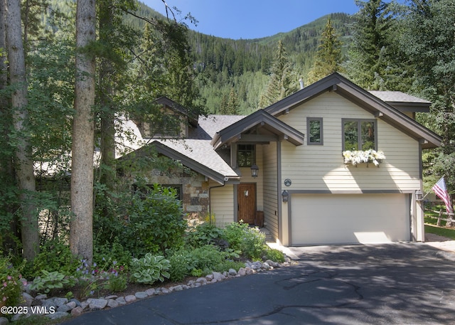 4030 Bighorn Rd Lot 1-B, Vail, CO 81657 - view of front of home featuring a garage, asphalt driveway, roof with shingles, a mountain view, and a view of trees
